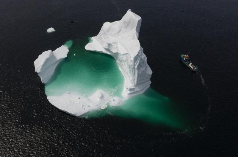 This aerial photo shows the boat of Captain Edward Kean passing an iceberg in Bonavista Bay on June 29, 2019 in Newfoundland, Canada. Johannes Eisele/AFP