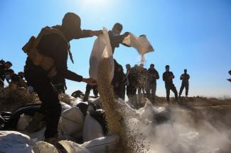 Members of the security forces of Syria's new authorities empty sacks of Captagon into a ditch to burn them in a field